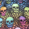 Detalle del tejido estampado con calaveras fluor en tonos vivos sobre fondo negro.